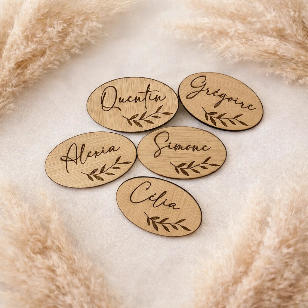 Marque-place en bois personnalisé 7x4 cm avec prénom en écriture calligraphique et motif feuillage. Idéal pour mariage et événement.